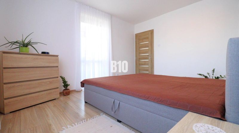 Schlafzimmer mit Bett, Schrank und Pflanzen auf dem Boden mit Holzdekor in einem Einfamilienhaus.