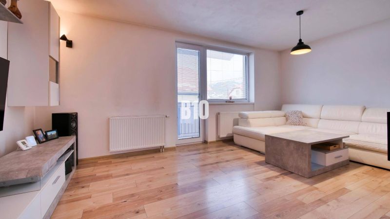 Wohnzimmer in einer 3-Zimmer-Wohnung mit Holzboden und weißem Sofa.