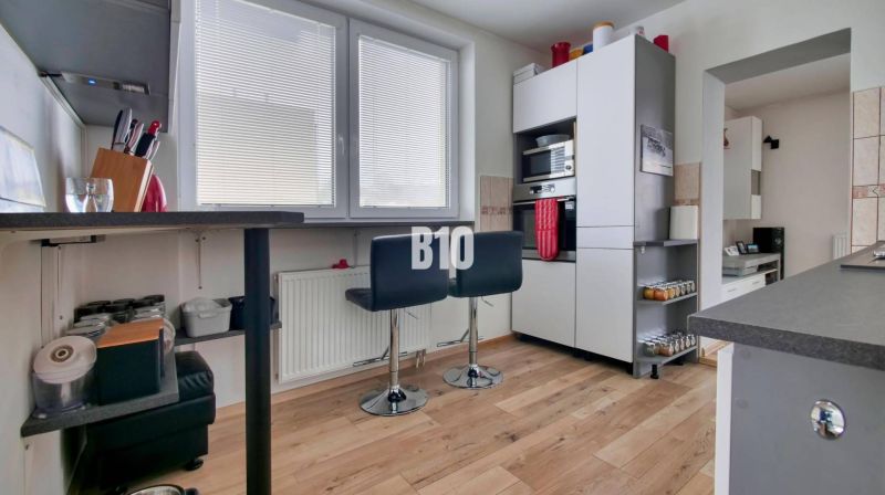 Küche mit Barhockern und Holzboden in einer 3-Zimmer-Wohnung.