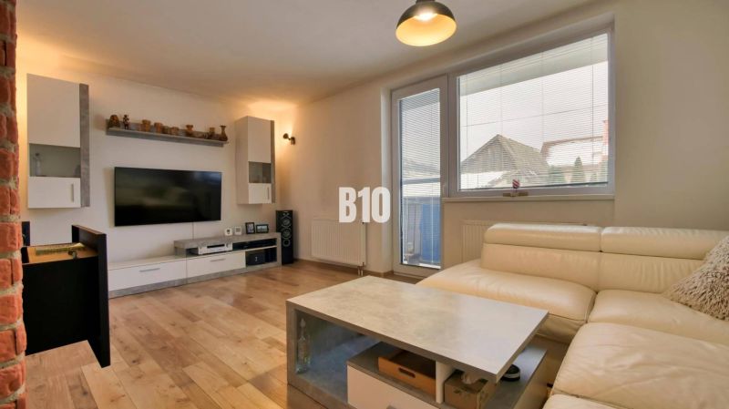 Wohnzimmer in einer 3-Zimmer-Wohnung mit Holzboden und einem bequemen weißen Sofa.