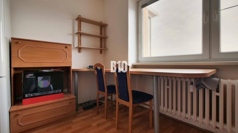 Arbeitsbereich mit Möbeln und Stuhl, Boden mit Holzdekor, Wand mit Regal.