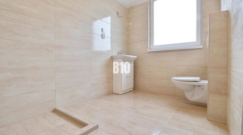 Badezimmer mit Waschbecken und Toilette in einem Einfamilienhaus mit Fliesenverkleidung.