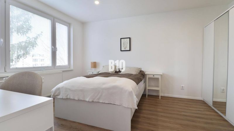 Helles Schlafzimmer mit Holzdekorboden in einer 3-Zimmer-Wohnung mit Einbauschrank.