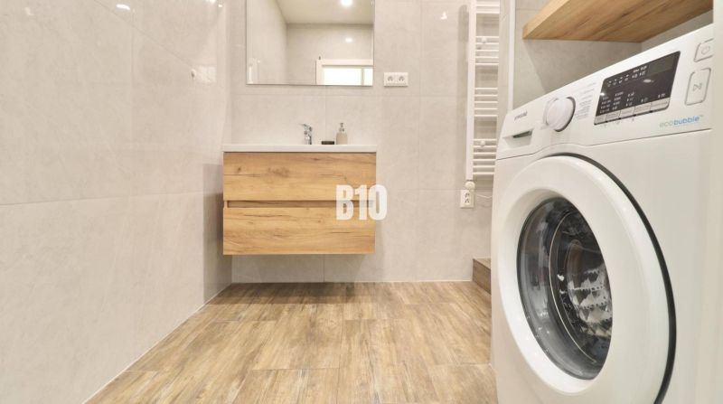 Badezimmer in einer 3-Zimmer-Wohnung mit Waschmaschine und Bodenbelag in Holzoptik.