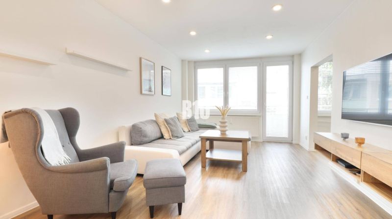 Wohnzimmer mit Sofa, Sessel und Holzboden in einer 3-Zimmer-Wohnung.