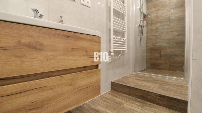 Badezimmer in einer 3-Zimmer-Wohnung mit Boden und Fliesen in Holzoptik.