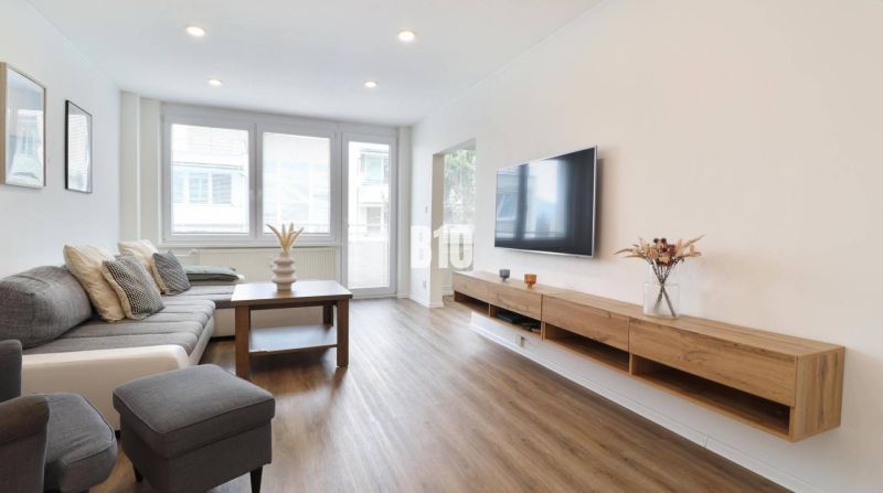 Wohnzimmer in einer 3-Zimmer-Wohnung mit Holzboden und Sofa.