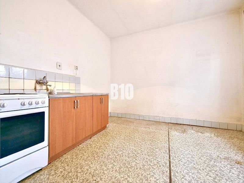 Küche in einem Einfamilienhaus mit Küchenzeile, Herd und Fliesenboden.