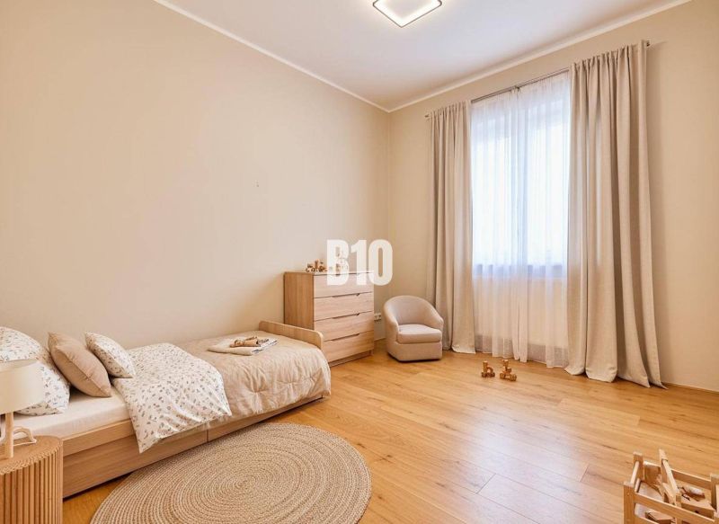 Kinderzimmer mit Bett, Sessel und Kommode, mit Holzboden.