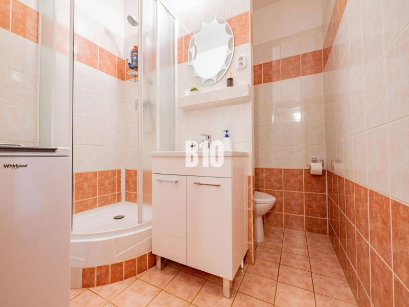 Badezimmer in einer 2-Zimmer-Wohnung mit Fliesen, einer Duschkabine und einem Unterschrank für das Waschbecken.