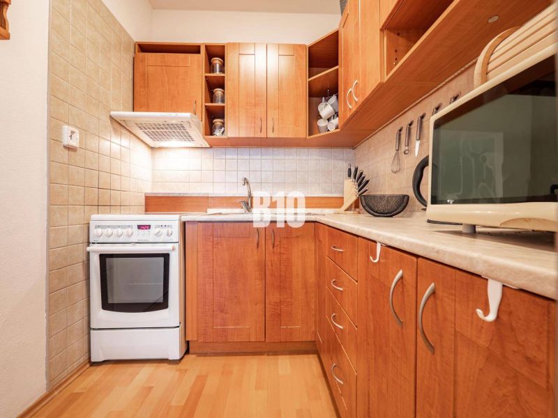 Küche in einer 2-Zimmer-Wohnung mit Holzboden und Schränken.