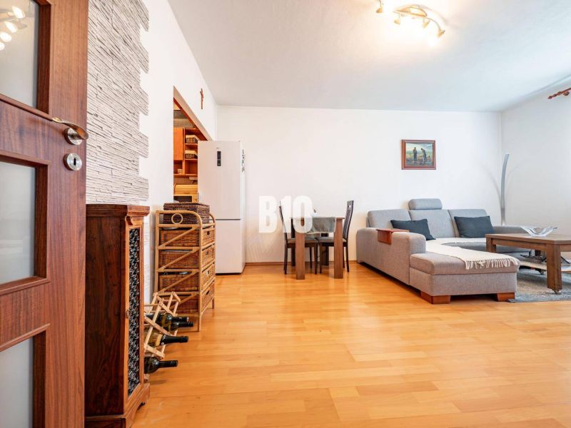 Wohnzimmer in einer 2-Zimmer-Wohnung mit Holzboden, Sofa und Esstisch.