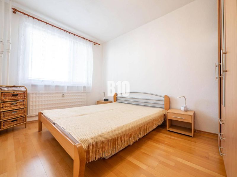 Schlafzimmer in einer 2-Zimmer-Wohnung mit einem Bett und einem Boden in Holzoptik.