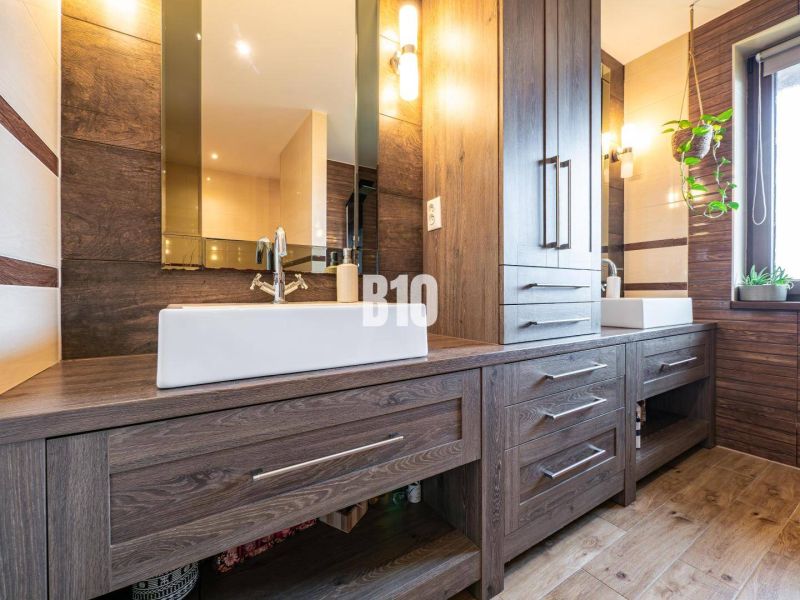 Badezimmer eines Einfamilienhauses mit Schränken und Boden in Holzoptik.