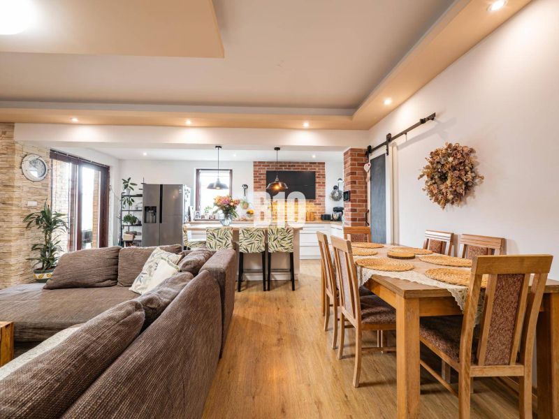 Offener Raum in einem Einfamilienhaus mit Sofa, Küche und Esstisch, Boden mit Holzdekor.