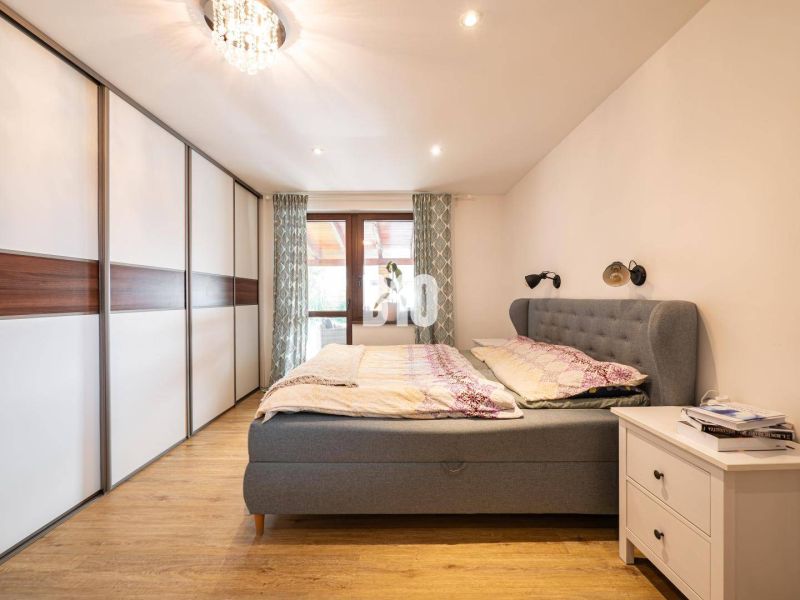 Schlafzimmer mit Holzboden, Kleiderschrank und gepolstertem Bett in einem Einfamilienhaus.