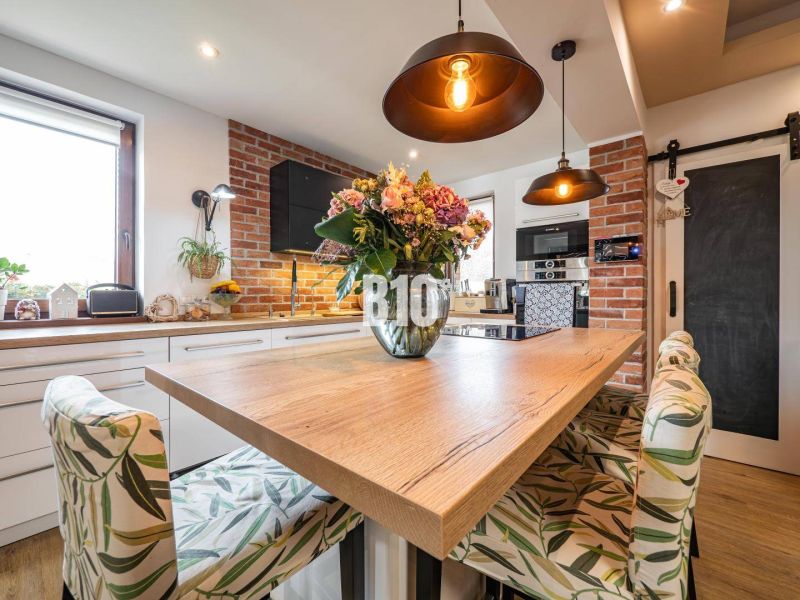 Küche in einem Einfamilienhaus mit Esstisch, Holzboden und Ziegelverkleidung.