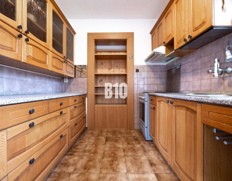 Küche in einem Einfamilienhaus mit Holzschränken und Fliesenboden.