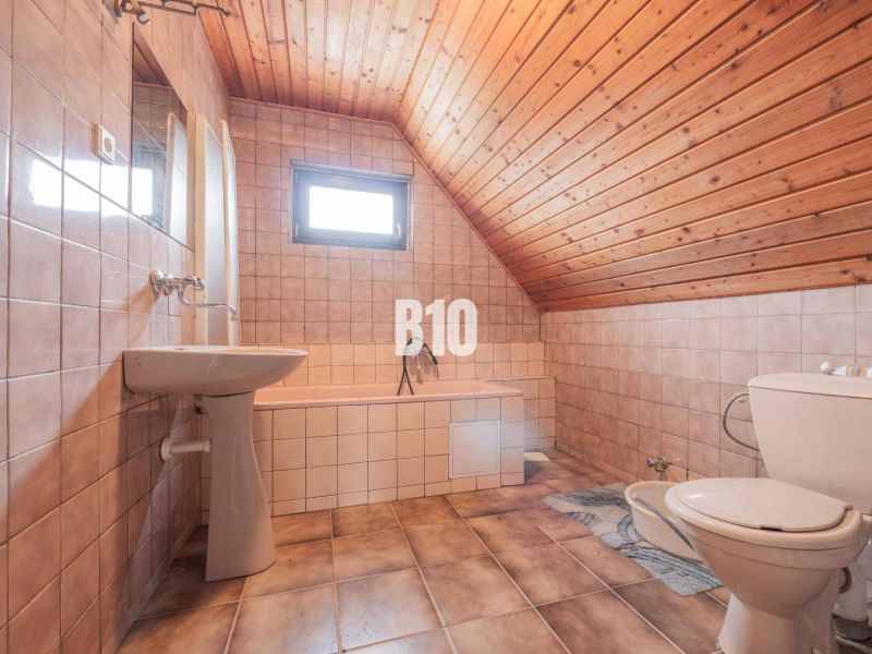 Ein Badezimmer in einem Einfamilienhaus mit Keramikfliesen und einer Holzdecke.