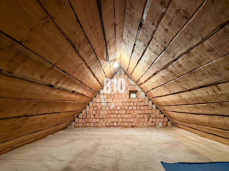 Podkrovný priestor s drevenými stenami a tehlovou stenou v rodinnom dome.

Dachboden mit Holzwänden und einer Ziegelwand in einem Einfamilienhaus.