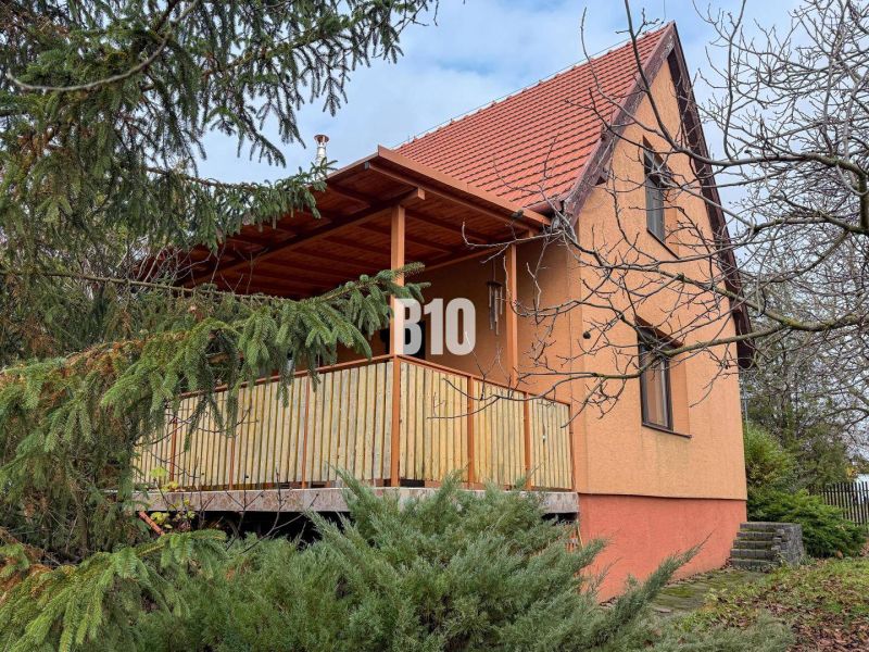 Ein Einfamilienhaus in Vlkas, umgeben von Grün, traditionell mit einem schrägen Dach, einem Holzbalkon.