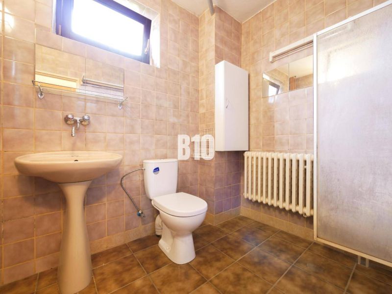 Badezimmer in einem Einfamilienhaus mit Waschbecken, Toilette und Duschkabine. Fliesendekor.