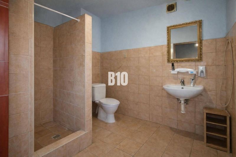 Badezimmer in Produktionsräumen mit Toilette, Waschbecken und Duschkabine.