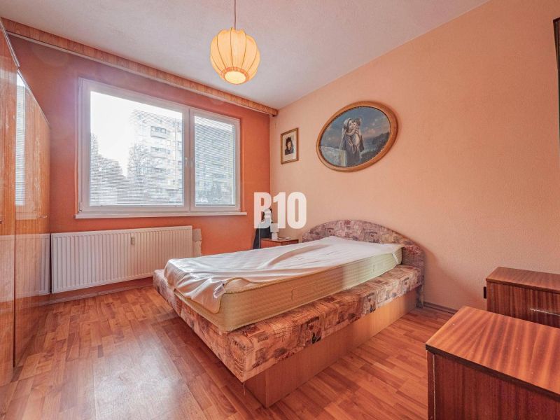 Schlafzimmer in einer 3-Zimmer-Wohnung mit Bett, Schrank und Boden in Holzoptik.