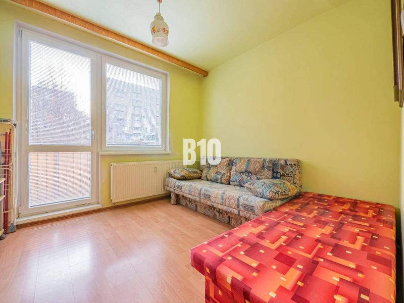 Ein Zimmer in einer 3-Zimmer-Wohnung mit einem Sofa und einem Boden in Holzoptik.