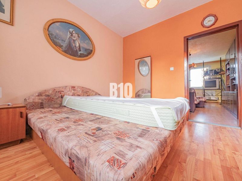 Schlafzimmer mit Sofa, Bild und Boden mit Holzdekor in einer 3-Zimmer-Wohnung.