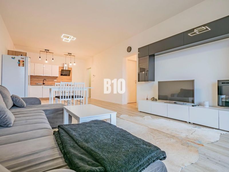 Wohnzimmer mit Küche, weiße Möbel, Sofa und Boden mit Holzdekor.
