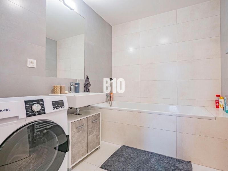 Badezimmer mit Badewanne, Waschbecken und Waschmaschine in einer 3-Zimmer-Wohnung.