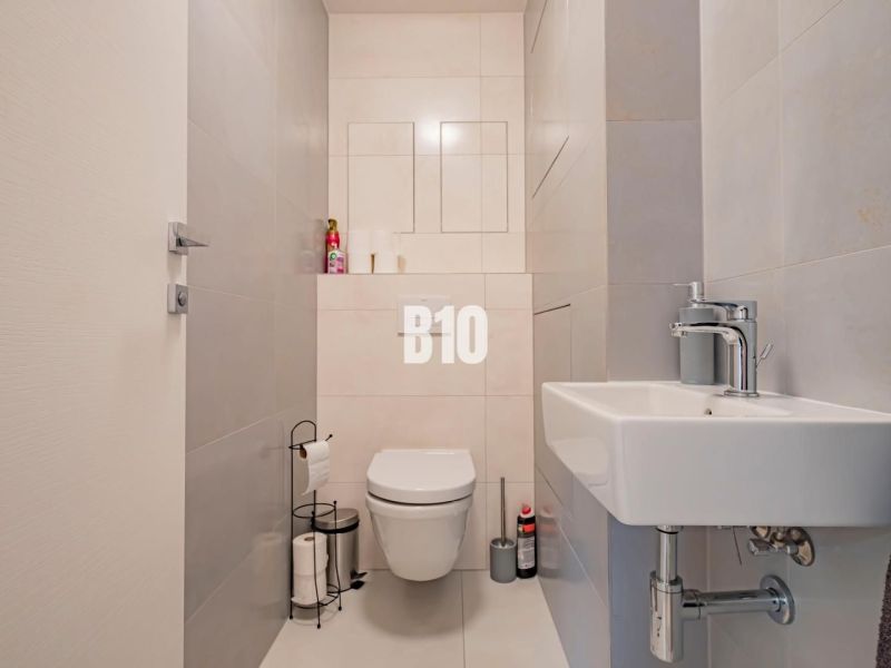 Badezimmer in einer 3-Zimmer-Wohnung mit einfachen hellen Fliesen und sanitären Einrichtungen.
