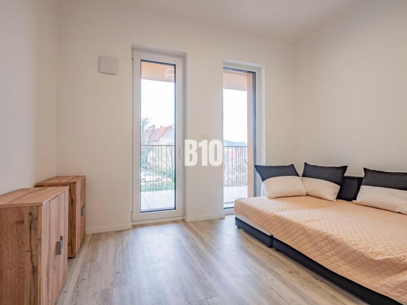 Ein Zimmer in einer 3-Zimmer-Wohnung mit einem Sofa, Schränken und einem Boden in Holzoptik.