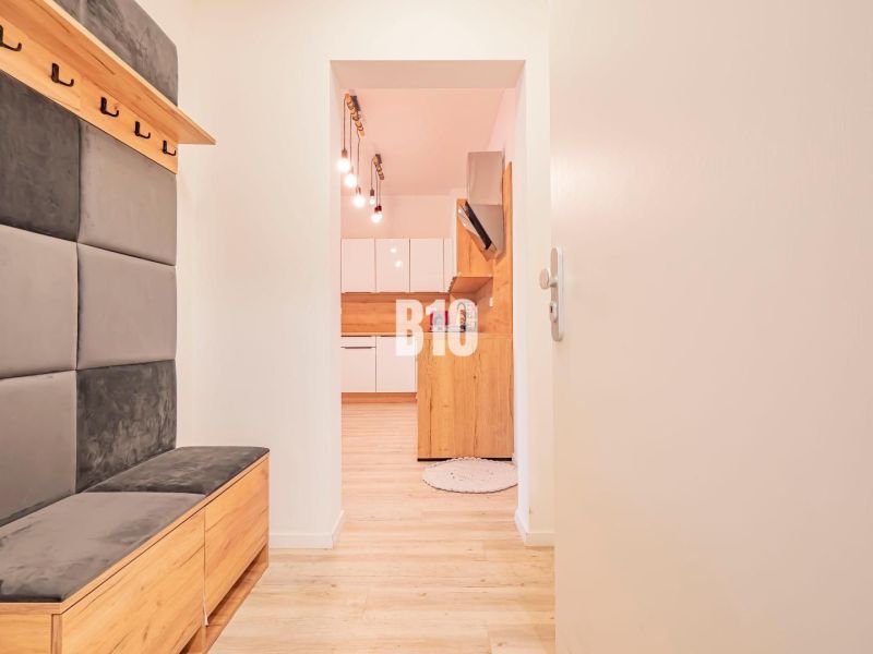 Eingangsflur mit Sitzgelegenheit und Blick in die Küche, 3-Zimmer-Wohnung mit Holzdekorboden.