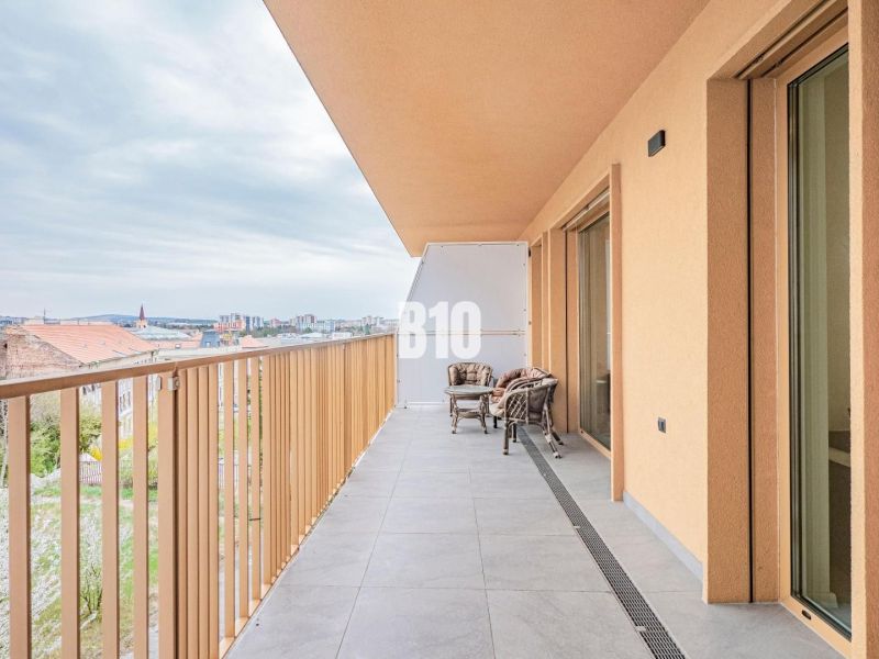 Balkon einer 3-Zimmer-Wohnung in Nitra mit Blick auf die Stadt und einer Sitzgelegenheit im Freien.