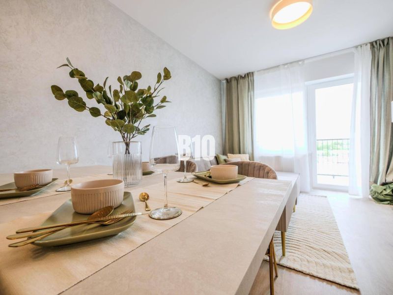 Esstisch in einer 2-Zimmer-Wohnung mit Tischdecken und Dekoration in hellen Farben.