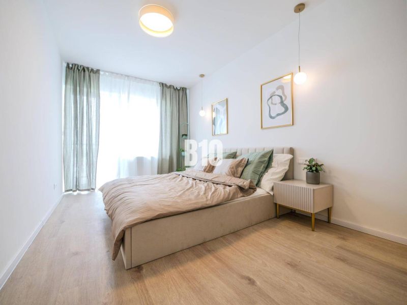 Helles Schlafzimmer in einer 2-Zimmer-Wohnung mit Holzboden und minimalistischen Möbeln.