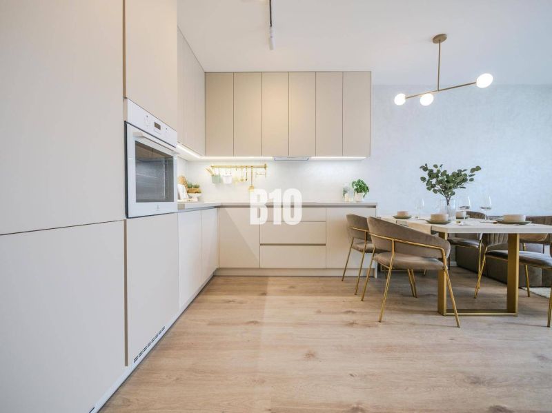 Helle Küche mit Esstisch und Holzboden in einer Zweizimmerwohnung.