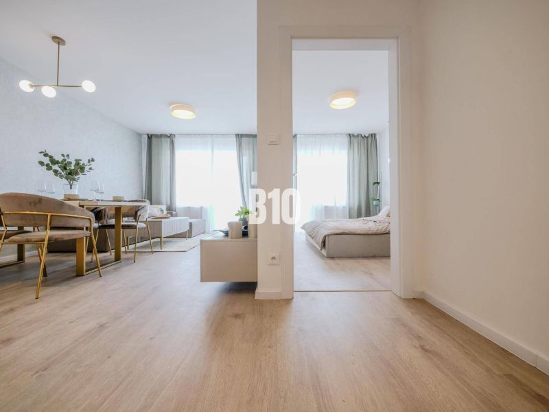 Innenraum einer 2-Zimmer-Wohnung mit Holzboden, Esstisch und Bett.