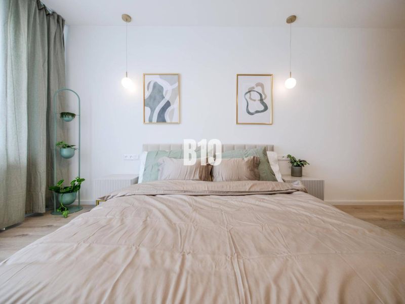 Doppelbett mit grünen Pflanzen und Holzboden in einer 2-Zimmer-Wohnung.