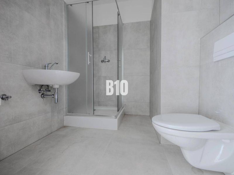 Badezimmer mit Waschbecken, Duschkabine und WC in einer Einzimmerwohnung.