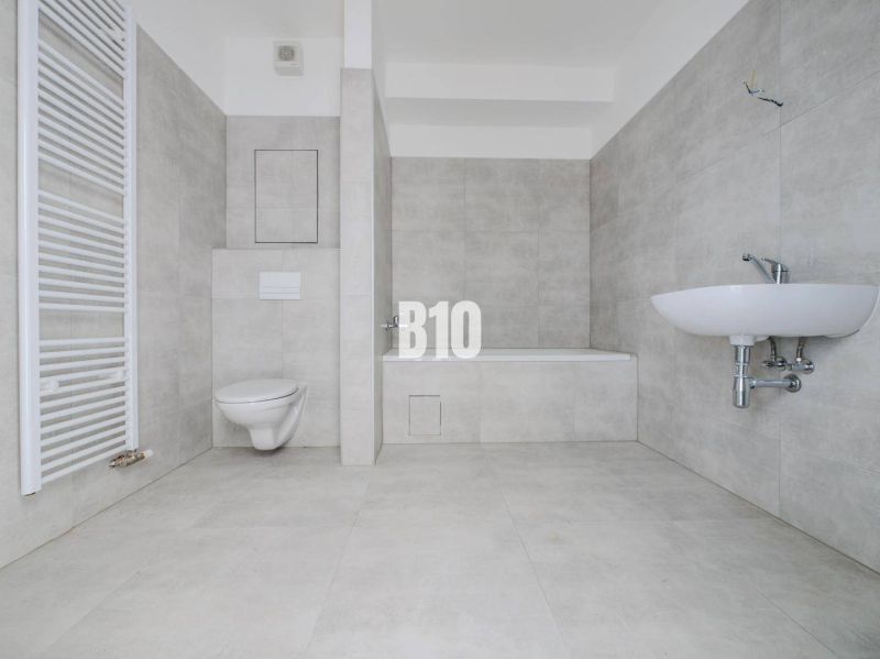 Badezimmer mit Badewanne, Waschbecken und Toilette in einer neuen 2-Zimmer-Wohnung.