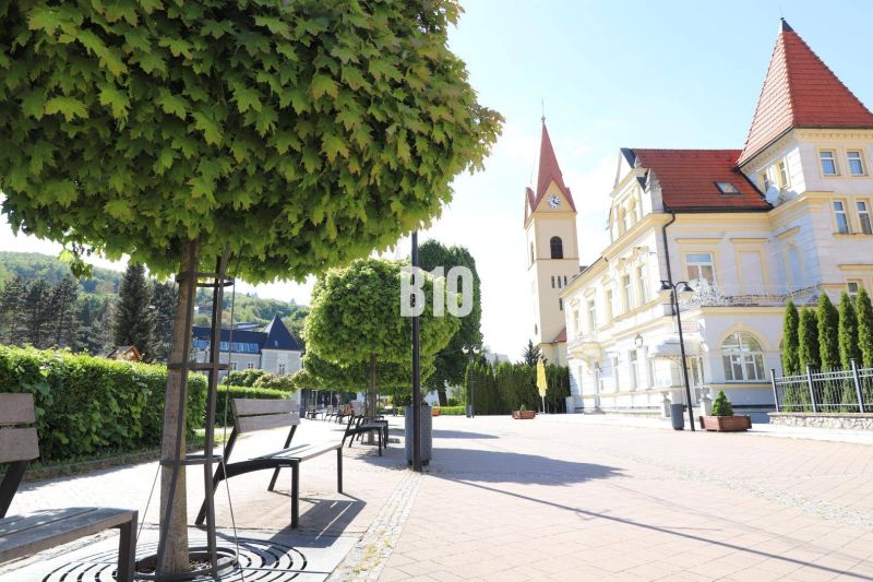 Der Stadtplatz in Trenčianske Teplice mit Bänken, Bäumen und historischer Architektur, Grundstücke - Wohnen.