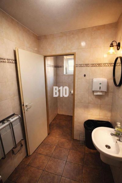 Badezimmer mit Waschbecken, weißem Seifenspender und Boden mit braunem Dekor im Gebäude.