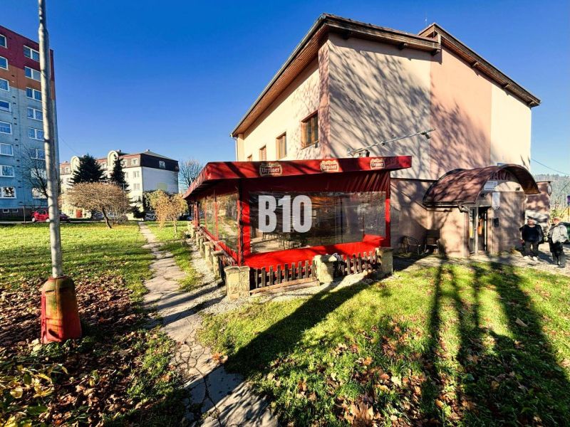 Ein Gebäude in Čadca mit Garten, Terrasse und roter Markise bei sonnigem Wetter.