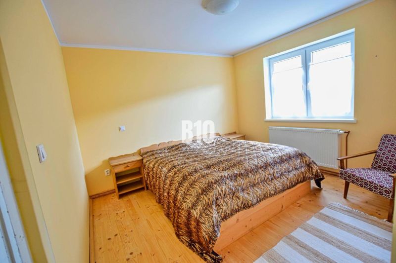 Ein Schlafzimmer mit Doppelbett, Holzmöbeln und einem Boden mit Holzdekor in einem Einfamilienhaus.