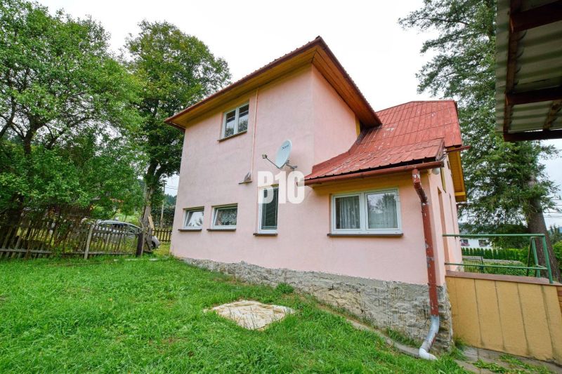 Einfamilienhaus in Makov mit rosa Fassade, Garten und Satellitenschüssel an der Wand.