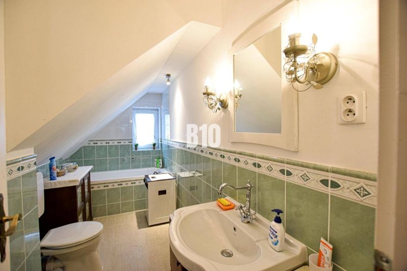 Ein Badezimmer in einem Einfamilienhaus mit grünen Fliesen und einer Dachschräge.