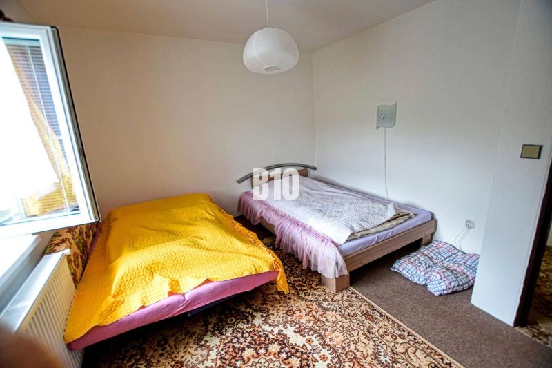 Ein Zimmer in der Hütte mit zwei Betten, einem offenen Fenster und einem gemusterten Teppich.